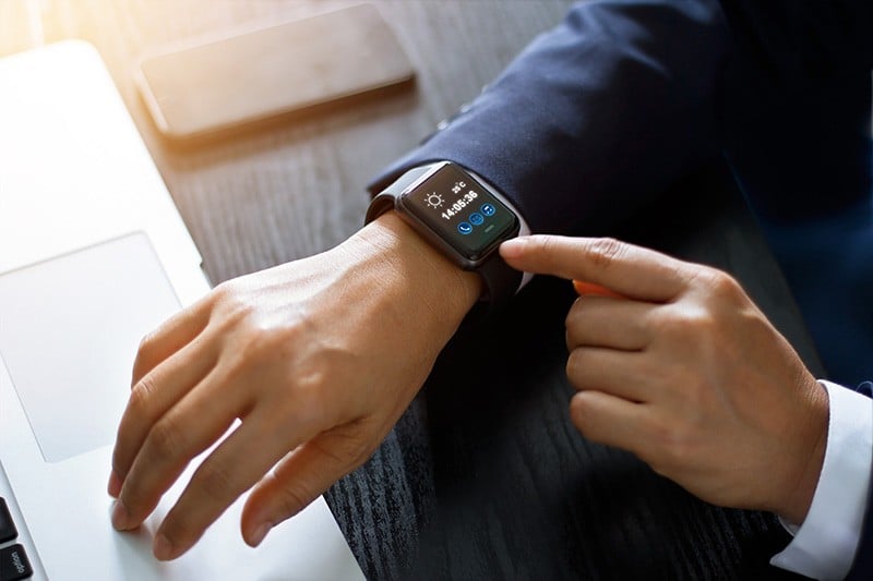wearables in business - hero image Wearables in business - Businessman using smart watch app over laptop and smartphone on working desk