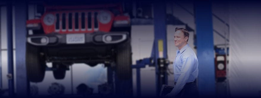 AAMCO-background A man wears a suit in a car workshop