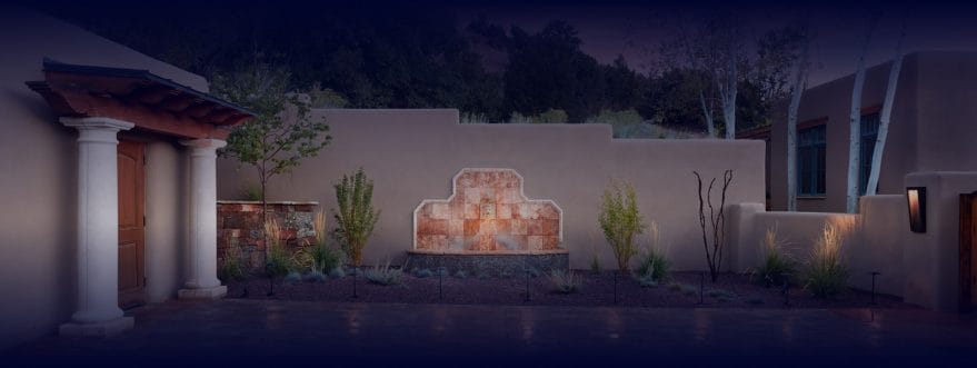 urbanna-background-2 Background image for Urbanna's case study showing a home courtyard with tiled wall fountain and landscape lighting at night