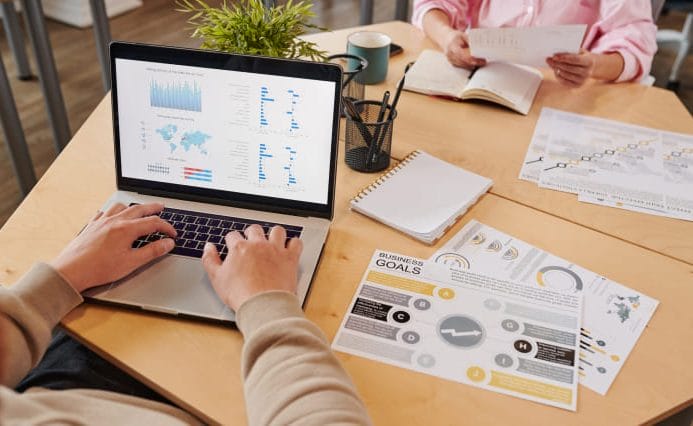 seo-services-quantifiable-results SEO analyst reviewing website performance data and reporting metrics on a laptop during a planning meeting