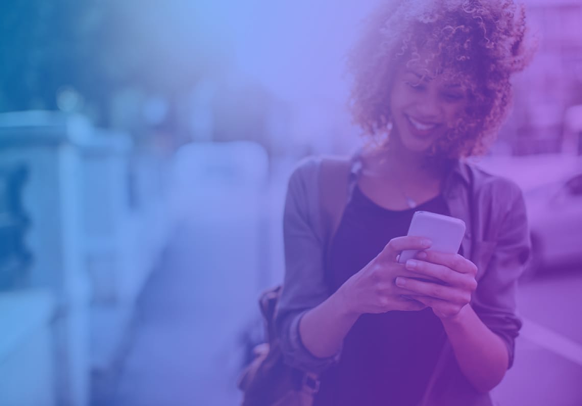 saas-marketing-agency-mavenir-image01 Woman with curly hair smiling while using a smartphone outdoors, with a teal blue color overlay