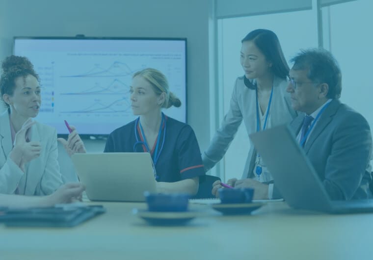 saas-marketing-agency-p360-image02 Four healthcare professionals including a nurse, a physician and two executives collaborating around a laptop in a meeting room with data charts visible on a screen behind them, overlaid with a blue and purple gradient