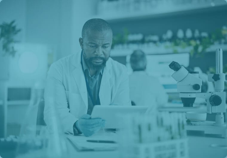 saas-marketing-agency-zontal-image02 A scientist in a white lab coat reviewing data on a tablet at a laboratory workbench, with microscopes and sample racks visible nearby, overlaid with a teal color wash
